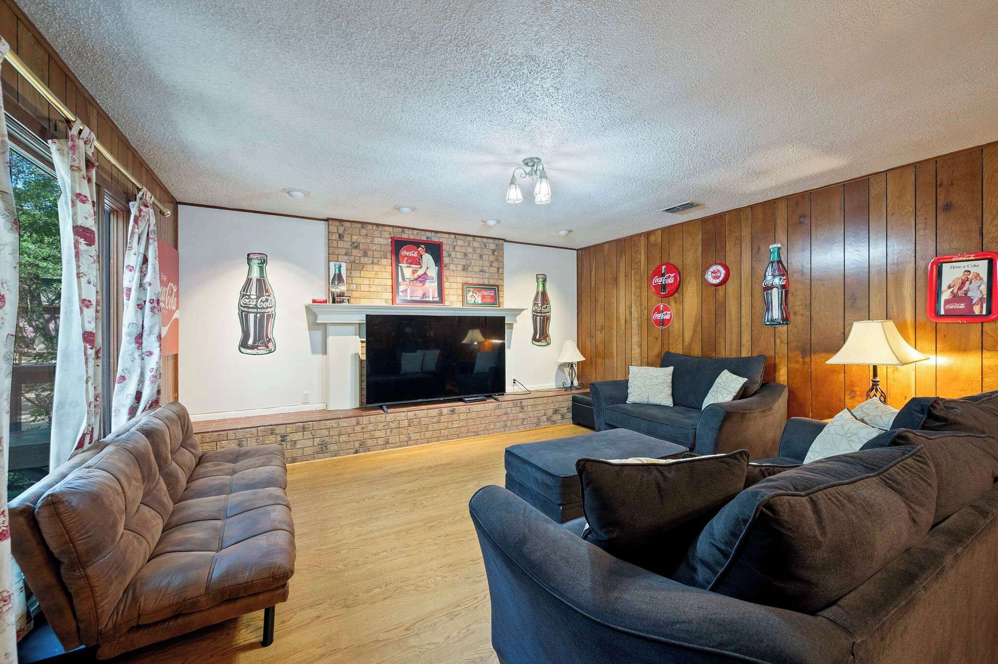 A living room with a fireplace, sofas, and wall decorations including Coca-Cola memorabilia.