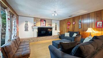 A living room with a fireplace, sofas, and wall decorations including Coca-Cola memorabilia.