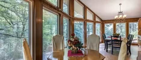 Un comedor con mesa de madera, sillas y una araña.