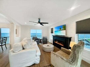 A modern living room with a fireplace, a television, and a view of the ocean. - Bay Haven | Modern contemporary w/ pools, fitness center, golf & more! (Greenbackville)