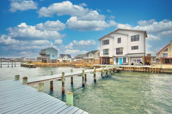 A waterfront property with a dock extending into the water, surrounded by houses with a clear sky above.