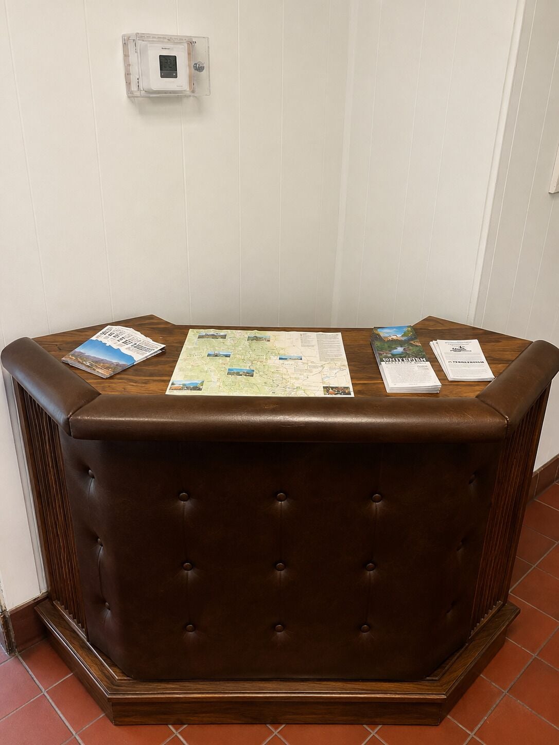 Un banc en cuir marron, sur lequel sont posées une carte et des brochures.
