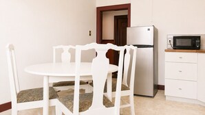 Una cocina pequeña con un refrigerador blanco, un microondas y una mesa de comedor con sillas.