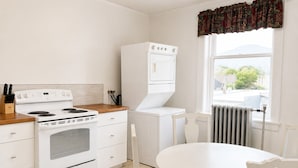 Una cocina con estufa, horno y microondas integrado. Hay una mesa de comedor con sillas y una ventana con vistas.