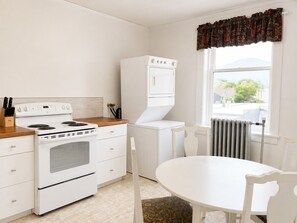 Una cocina con estufa, horno y microondas integrado. Hay una mesa de comedor con sillas y una ventana con vistas.