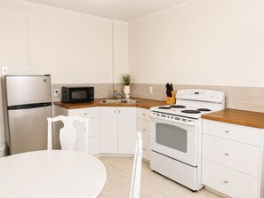 A kitchen with a refrigerator, microwave, stove, and white cabinets. - Grand Union Hotel (Coleman)