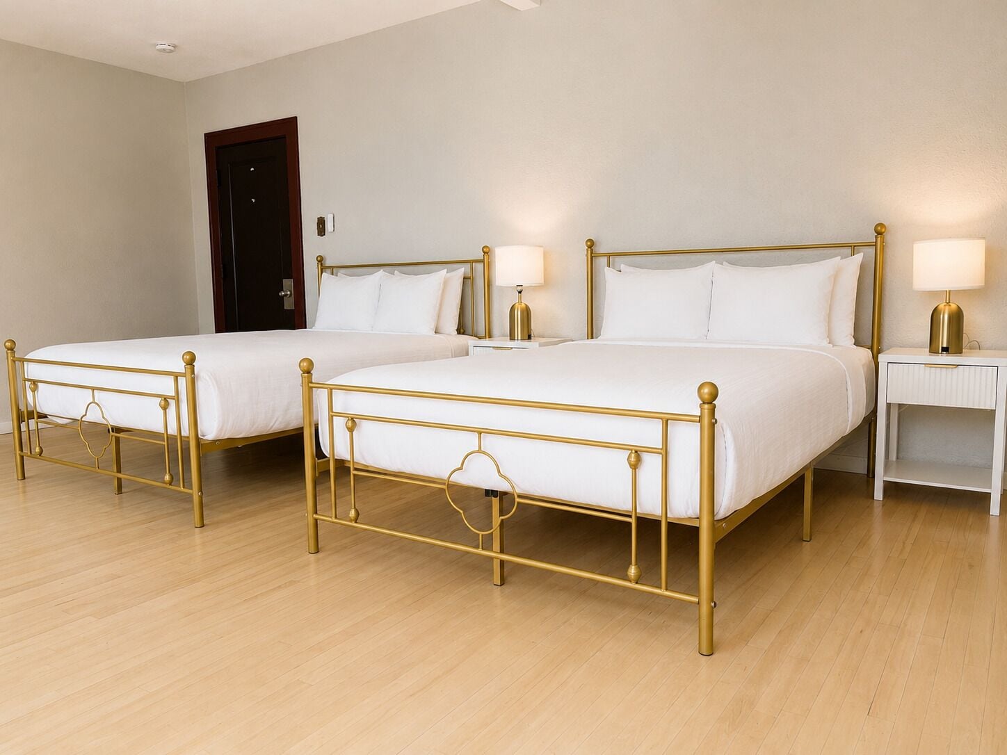 A hotel room with two single beds, a bedside table with a lamp, and a door.