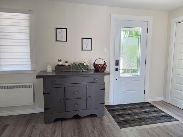 A room with a dark wooden dresser, a white door, and a window with blinds.