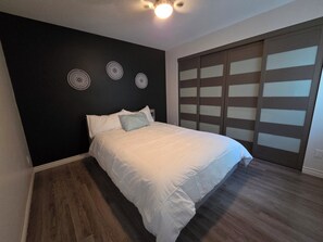 A bedroom with a bed, a dark wall, and a sliding door.
