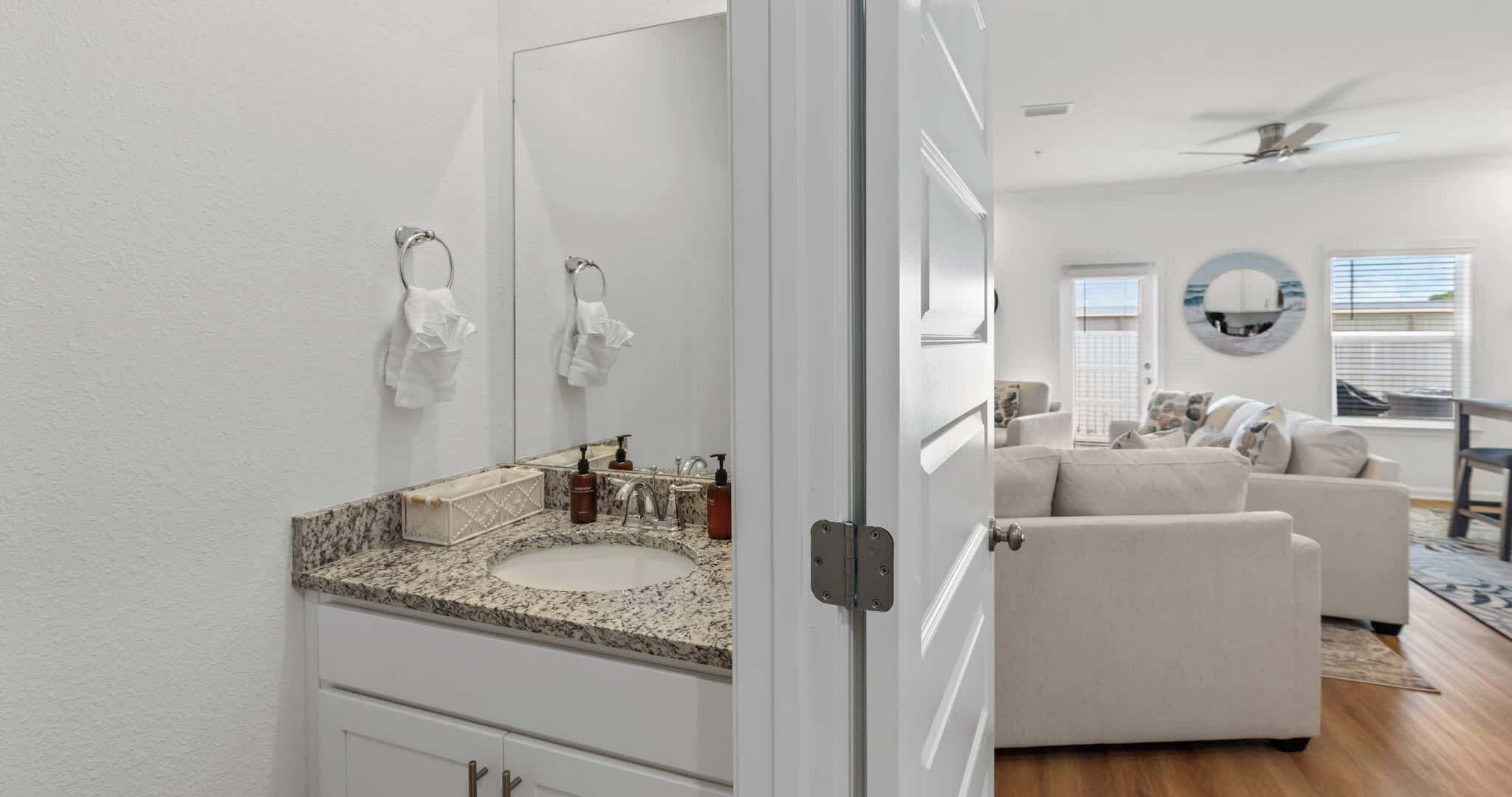 A bathroom with a granite countertop, a sink, and a mirror.