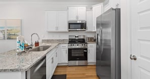 A modern kitchen with white cabinets, stainless steel appliances, and a granite countertop. - Easy Days at Lost Bay - 3bdr (Orange Beach)
