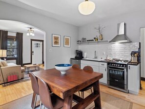 A modern kitchen with a stove, oven, and white backsplash. - Vintage Art Lodge 4BR/2BA Full Home in Bay View (Milwaukee)