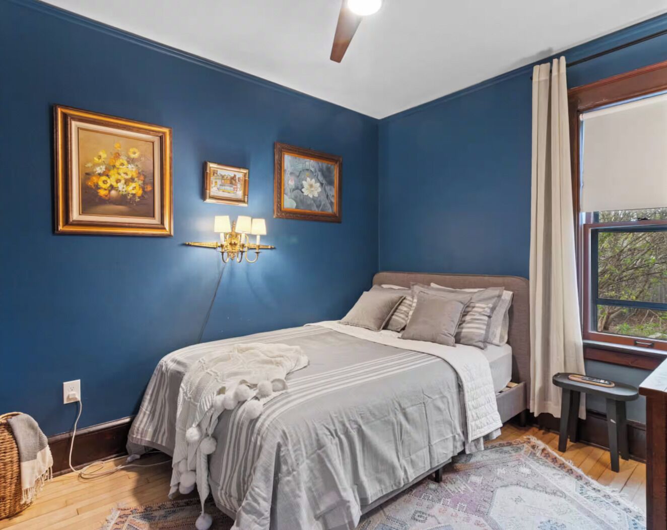 A bedroom with a bed, a nightstand, a lamp, and a window with curtains.