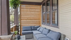 A covered outdoor seating area with a sectional sofa and a small table with a plant. - Vintage Art Lodge 4BR/2BA Full Home in Bay View (Milwaukee)