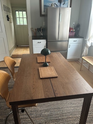 Uma mesa de jantar de madeira com uma luminária verde, dois jogos americanos e uma cadeira.