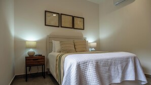 A bedroom with a bed, bedside tables, and wall art. - Palma Blanca 2BR Condos with Rooftop Pool and Ocean Views by Baja Sol PM (Cabo San Lucas)