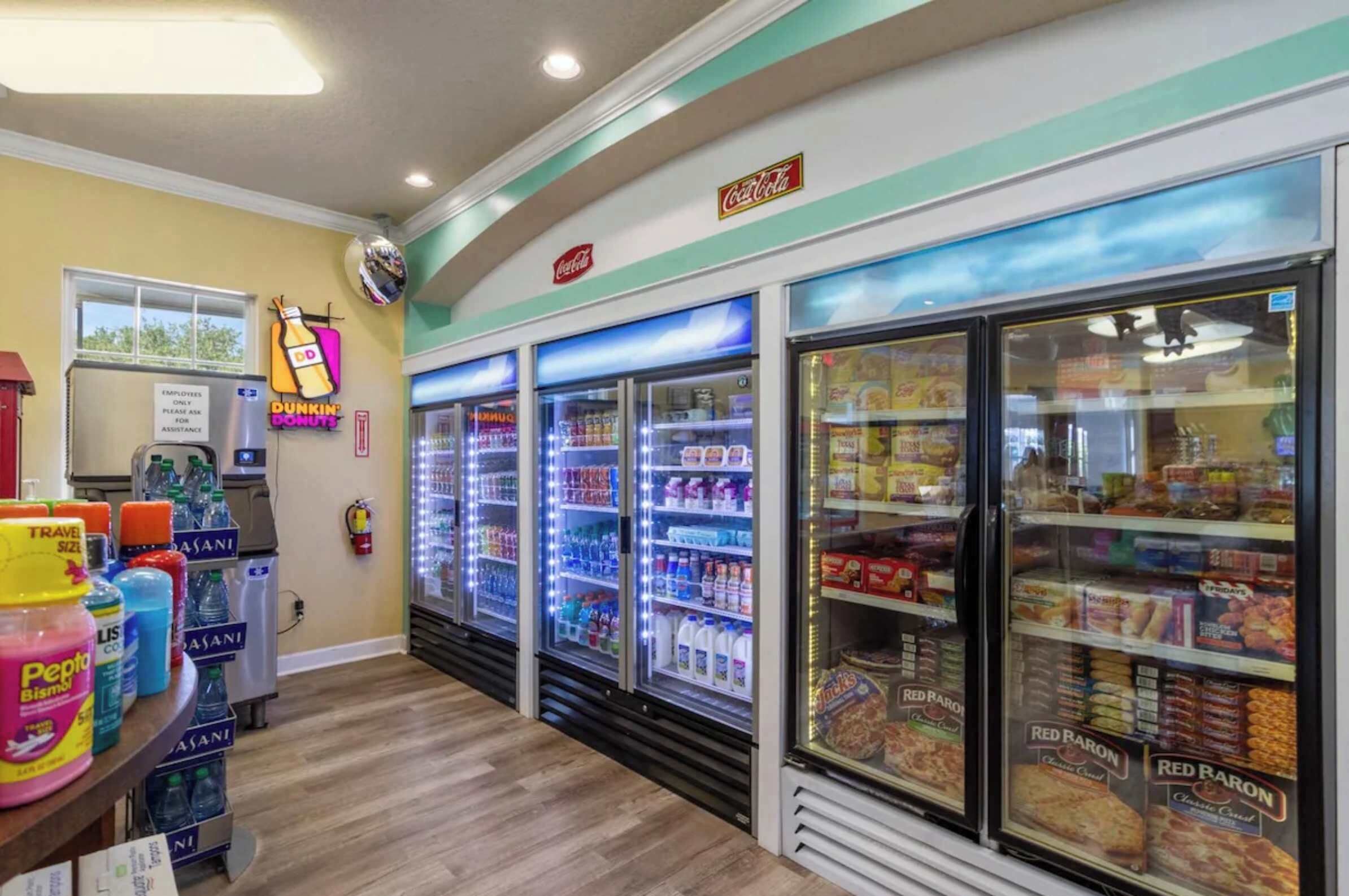 Interior de botiga amb vitrines refrigerades, un cartell de Coca-Cola i una promoció de Pepto Bismol.