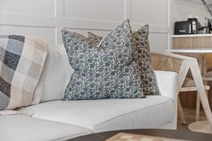 Ein weißes Sofa mit gemusterten Kissen und einer Decke.