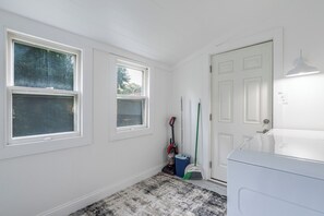 A laundry room with two windows, a door, and a washing machine.