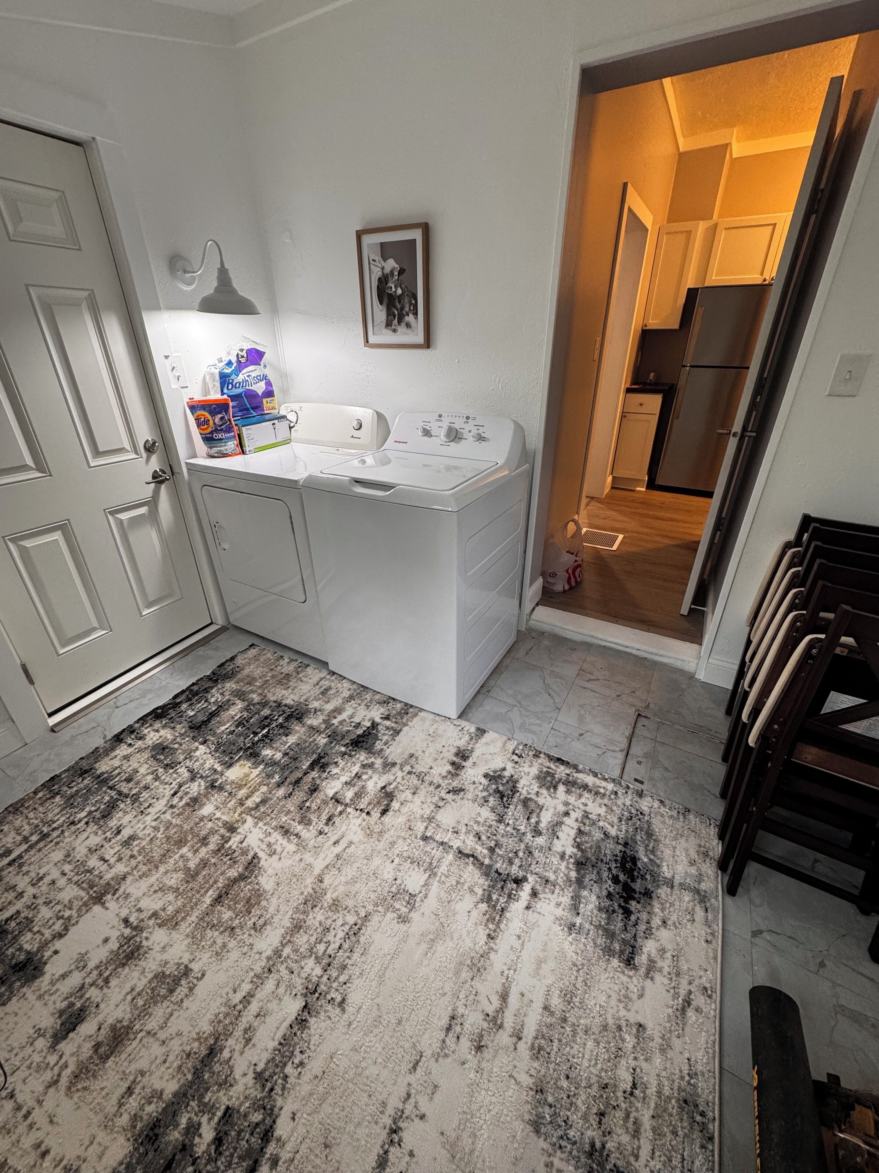 A laundry area with a washing machine, a drying rack, and a rug.