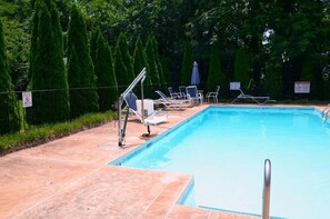 En swimmingpool med liggestole og et sikkerhedsskilte.