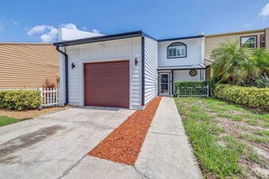 Ein Einfamilienhaus mit Garage, einer Veranda und einem kleinen Garten.