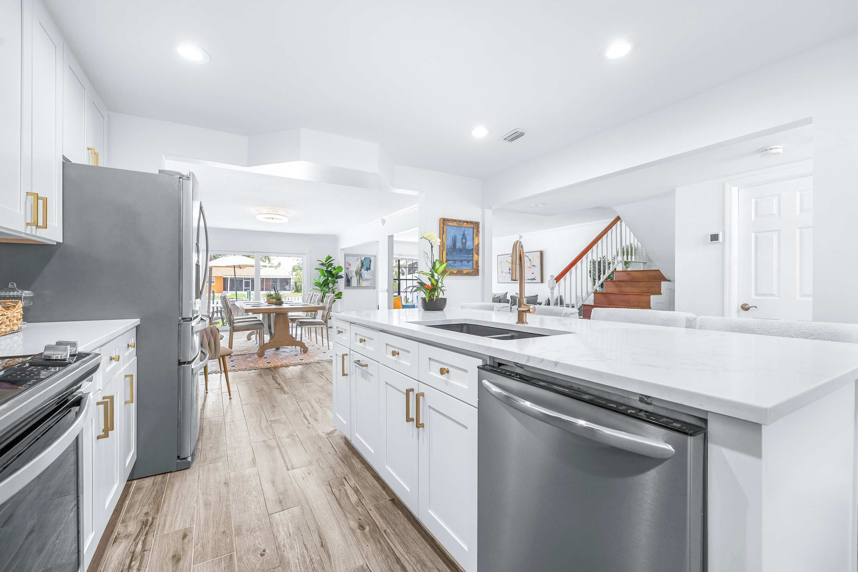 A modern kitchen with white cabinetry, stainless steel appliances, and a central island with a sink.