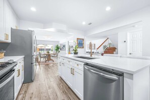 A modern kitchen with white cabinetry, stainless steel appliances, and a central island with a sink. - The Salty Siren's Cove 3bdr (Tampa)