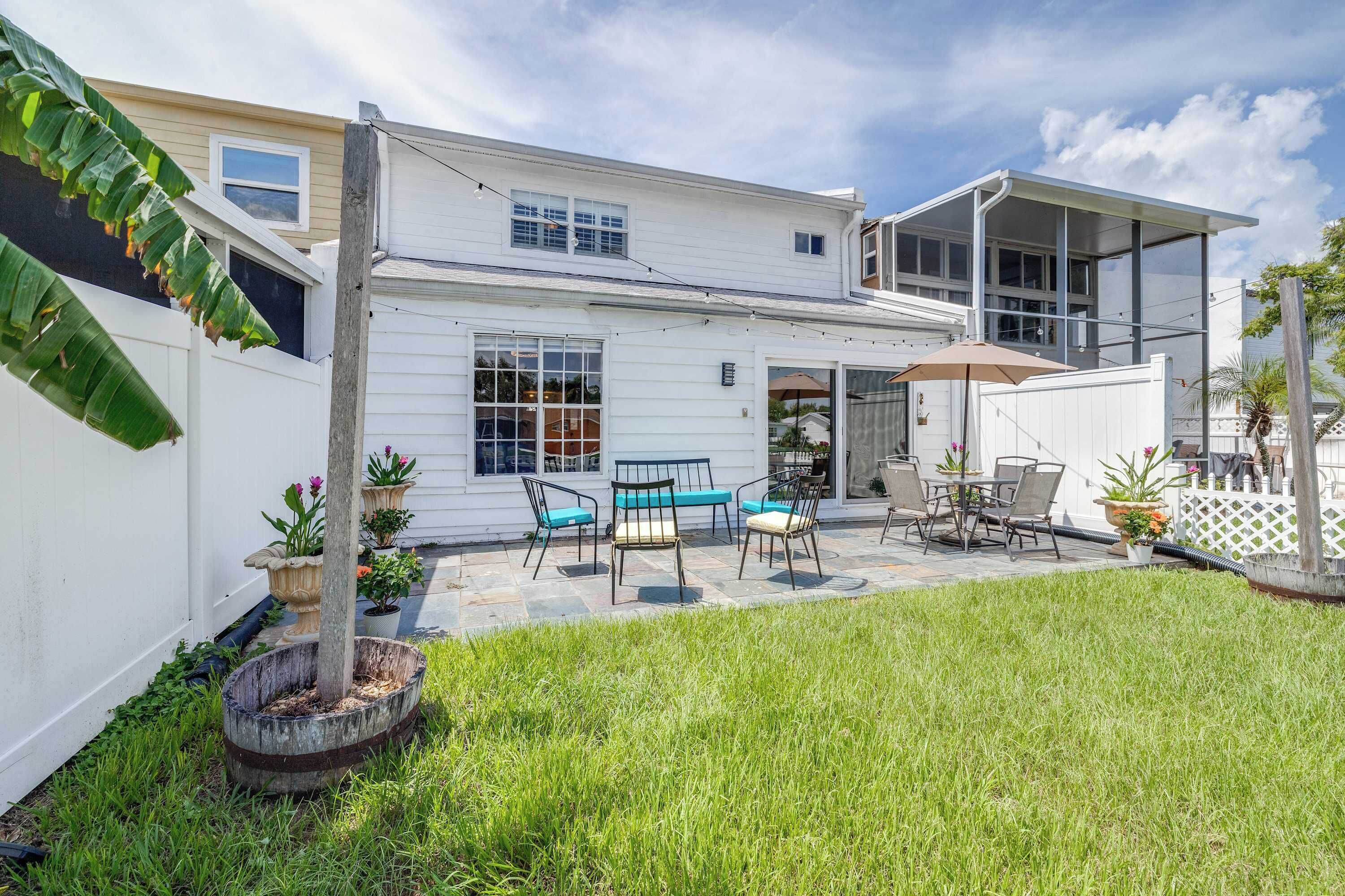 A residential property with a patio area, outdoor seating, and a white fence.