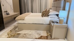 Ein Schlafzimmer mit Bett, Nachttisch, Lampe und einem gemusterten Teppich.