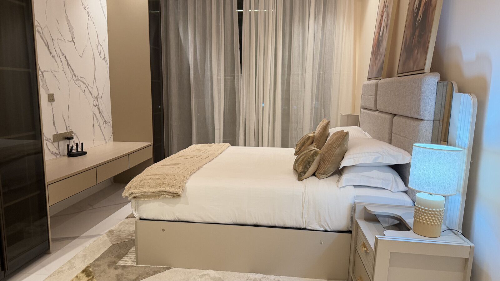 A modern bedroom with a bed, bedside tables, a lamp, and a window with curtains.