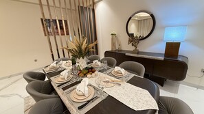 A dining area with a long table set for six, a dark wood sideboard, and a mirror on the wall. - Grand Residence 3 bedroom deluxe appartment with club house (Kinshasa)