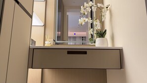 A wooden cabinet with a mirror, a white orchid plant, and a small white pot.