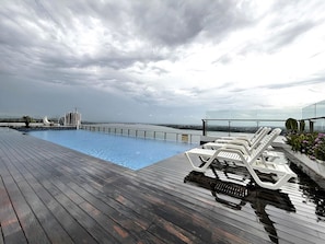 A rooftop pool with lounge chairs and a view of the city skyline.