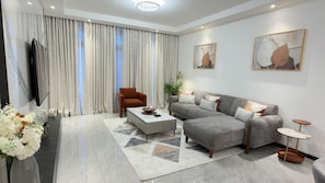 A modern living room with a sofa, armchair, coffee table, and decorative pillows.