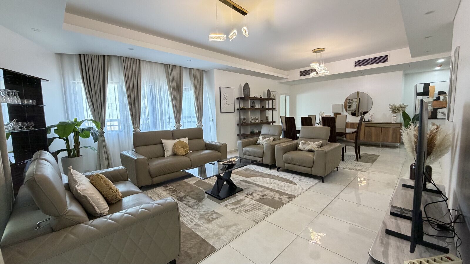 Una sala de estar moderna con un conjunto de sofá, sillones, una mesa de centro y un mueble para la televisión.