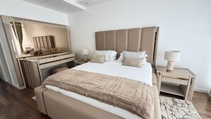 Een moderne slaapkamer met een bed, nachtkastjes, een bureau en een spiegel.