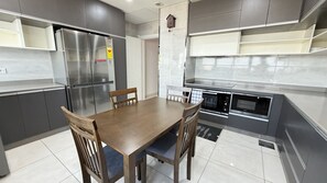 A modern kitchen with a dining table, chairs, stainless steel appliances, and grey cabinetry.