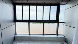 A room with a large window overlooking a body of water and a distant cityscape.