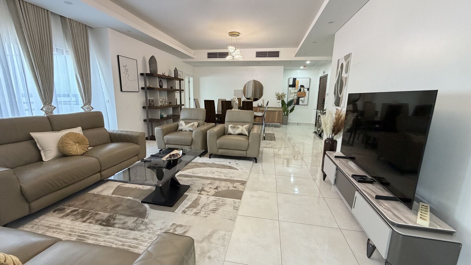 A modern living room with a sofa set, a coffee table, and a flat-screen TV.
