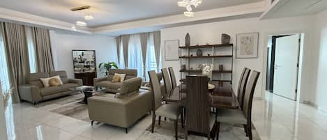 Een moderne woonkamer met een bank, fauteuil, eettafel en stoelen.