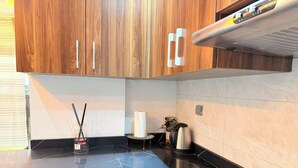 Una cuina moderna amb armaris de fusta, un taulell negre i un brollador d'acer inoxidable.