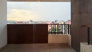 A balcony with a view of a cityscape, a railing, and a ceiling fan. - 1 bedroom Apartment in Kintambo Velodrome secure clean  with gym (Kinshasa)