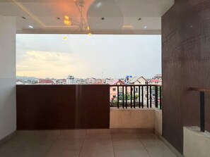 Ein Balkon mit Blick auf eine Stadtansicht, einem Geländer und einem Deckenventilator.
