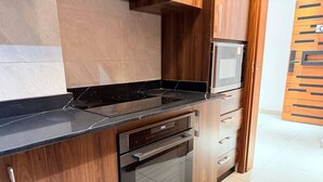 A kitchen with a built-in oven, microwave, and a wooden cabinet. - 1 bedroom Apartment in Kintambo Velodrome secure clean  with gym (Kinshasa)