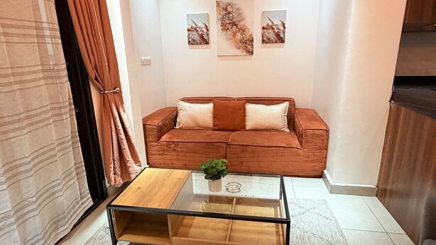 A living room with a sofa, a glass coffee table, and artwork on the wall. - 1 bedroom Apartment in Kintambo Velodrome secure clean  with gym (Kinshasa)