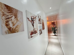 En gang med billedkunst på væggene og en potteplante.