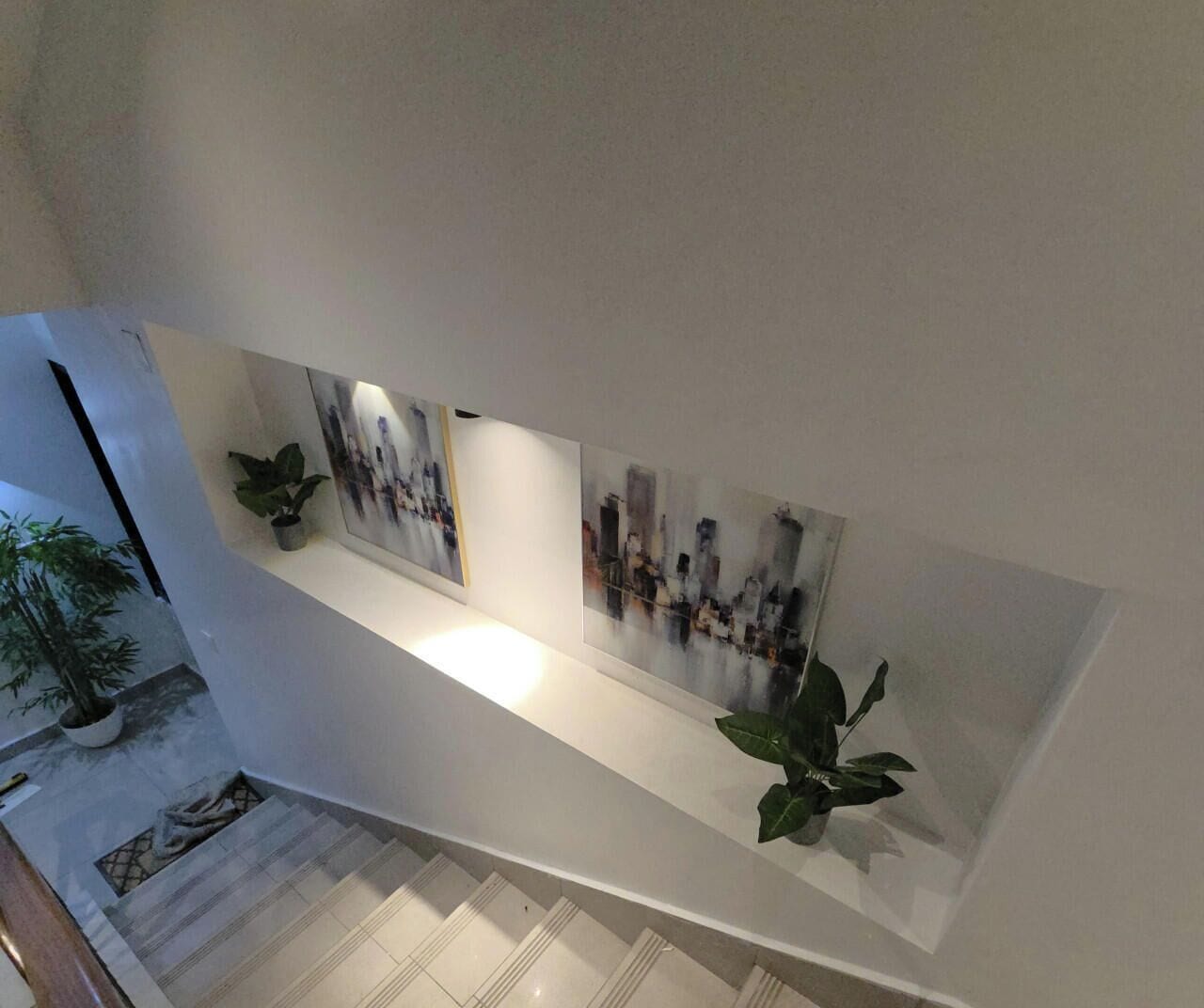 Een trap met een witte muur en kunstwerken.