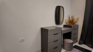 A modern bathroom vanity with a mirror, a small plant, and a cylindrical container.