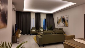 A modern living room with a sofa set, a coffee table, and a painting on the wall. - Luxury 3 Bedroom apartment (Kinshasa)
